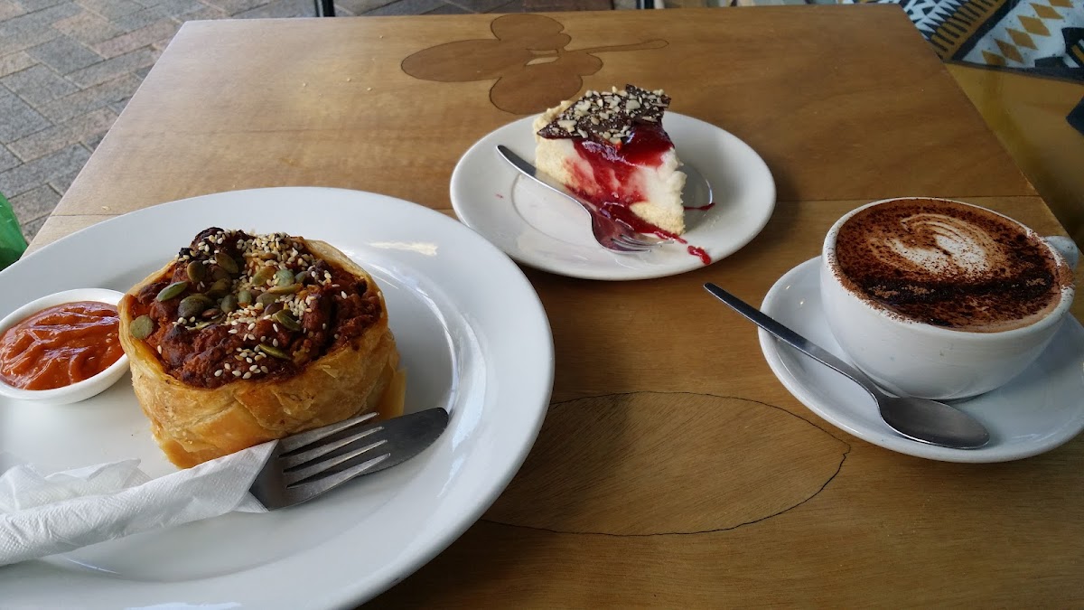 Savoury pastry, cheesecake and a cappuccino on an outdoor table